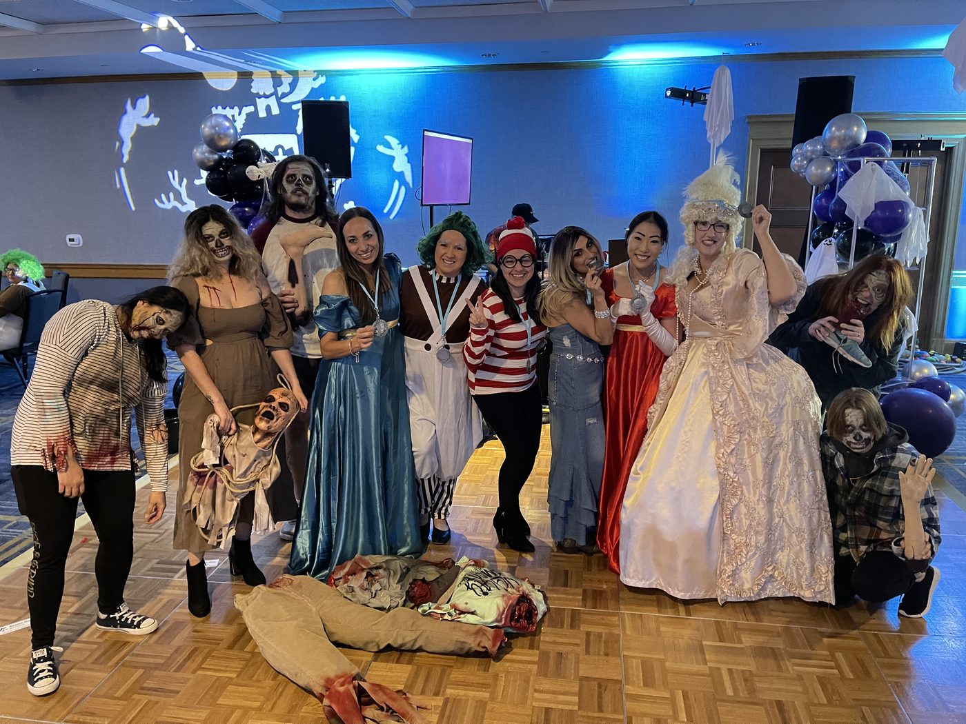 Costumed Zombie Hunt performers pose together in a venue lit blue and purple